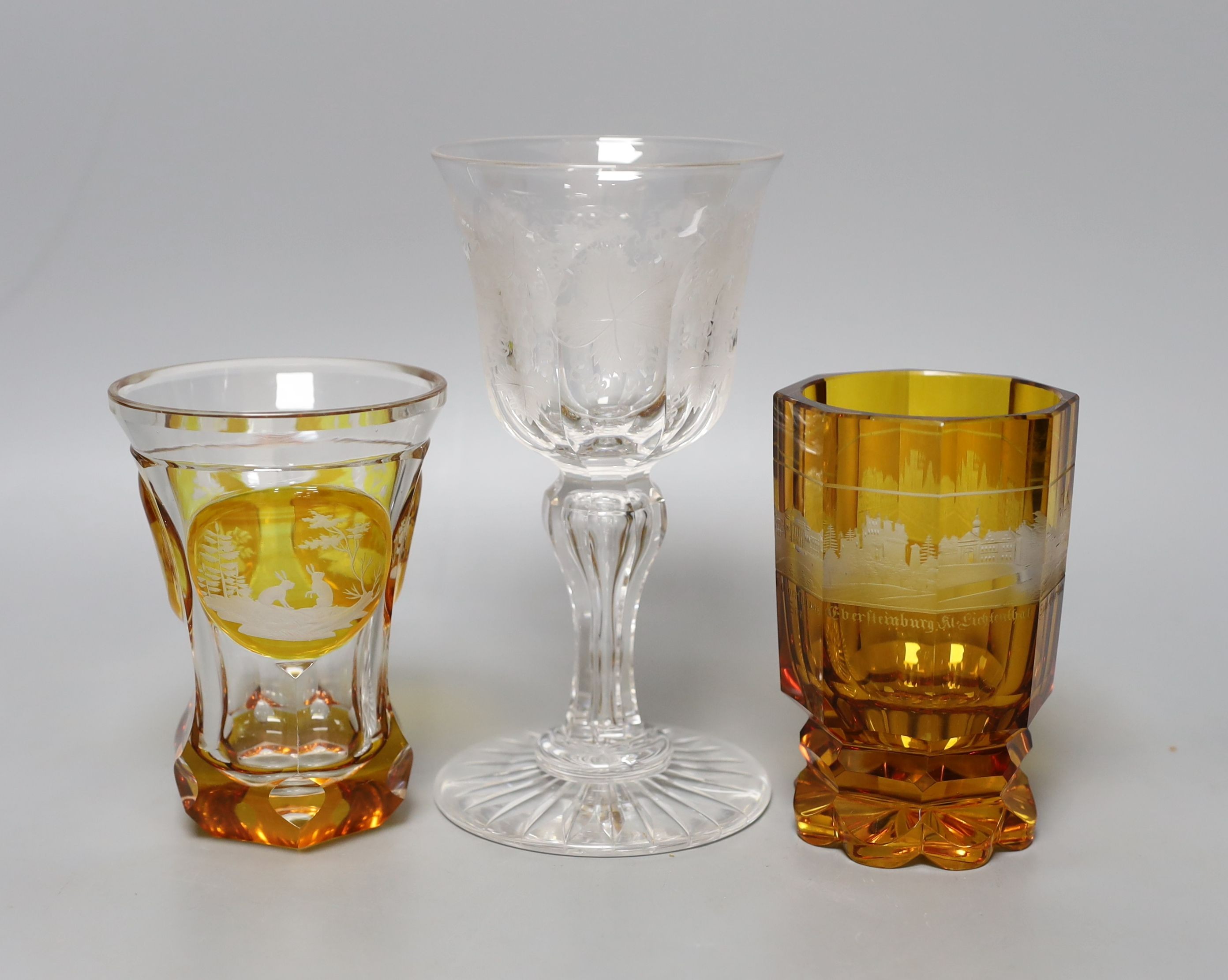 Two Bohemian wheel engraved amber flashed beakers, one with titled topographical views and a wheel engraved glass goblet (3) - tallest 18cm